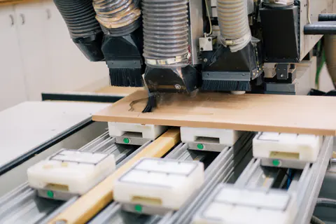 Husillo de una fresadora CNC cortando un panel de madera sujeto con ventosas