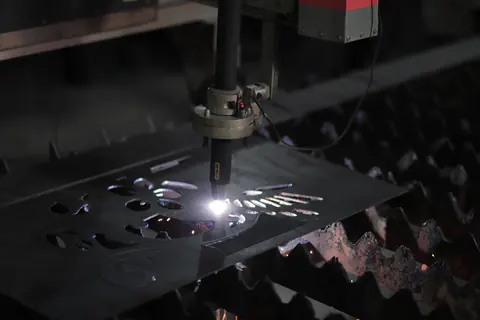 Antorcha de plasma CNC cortando formas en una chapa de acero entre chispas